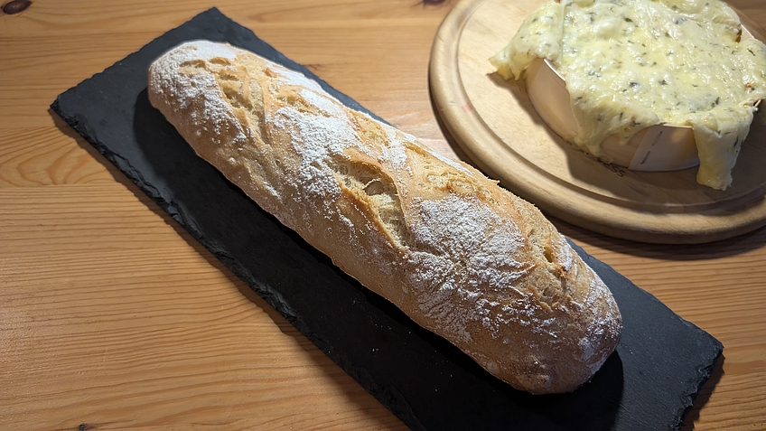 Baguette mit Ofenkäse im Hintergrund